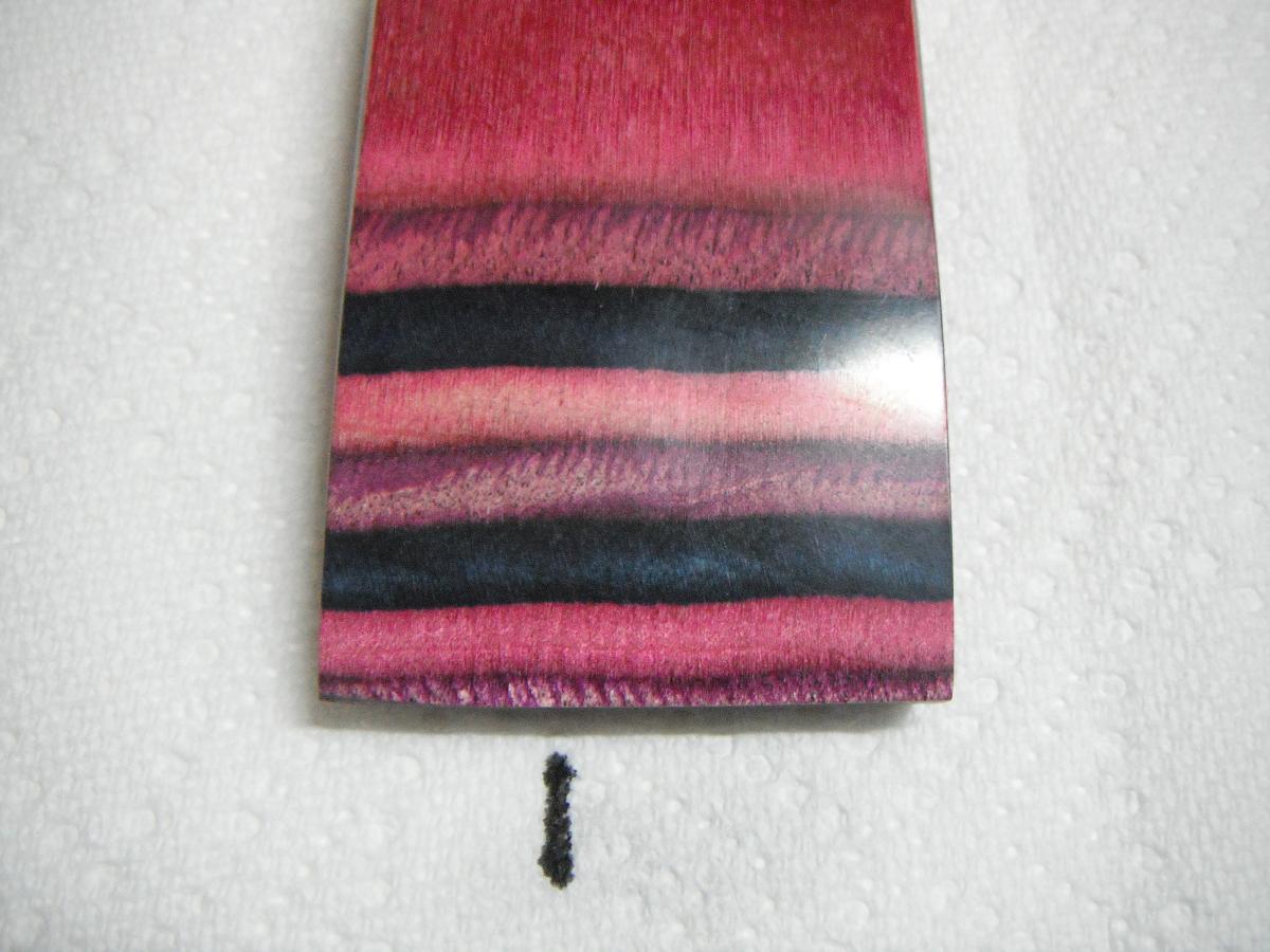 A piece of wood with a black and red stripe on it.