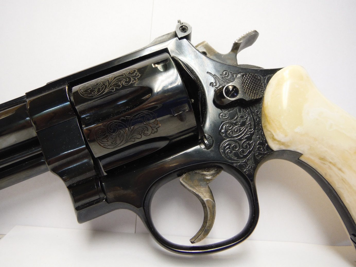 A black revolver with white grips and a bone handle.