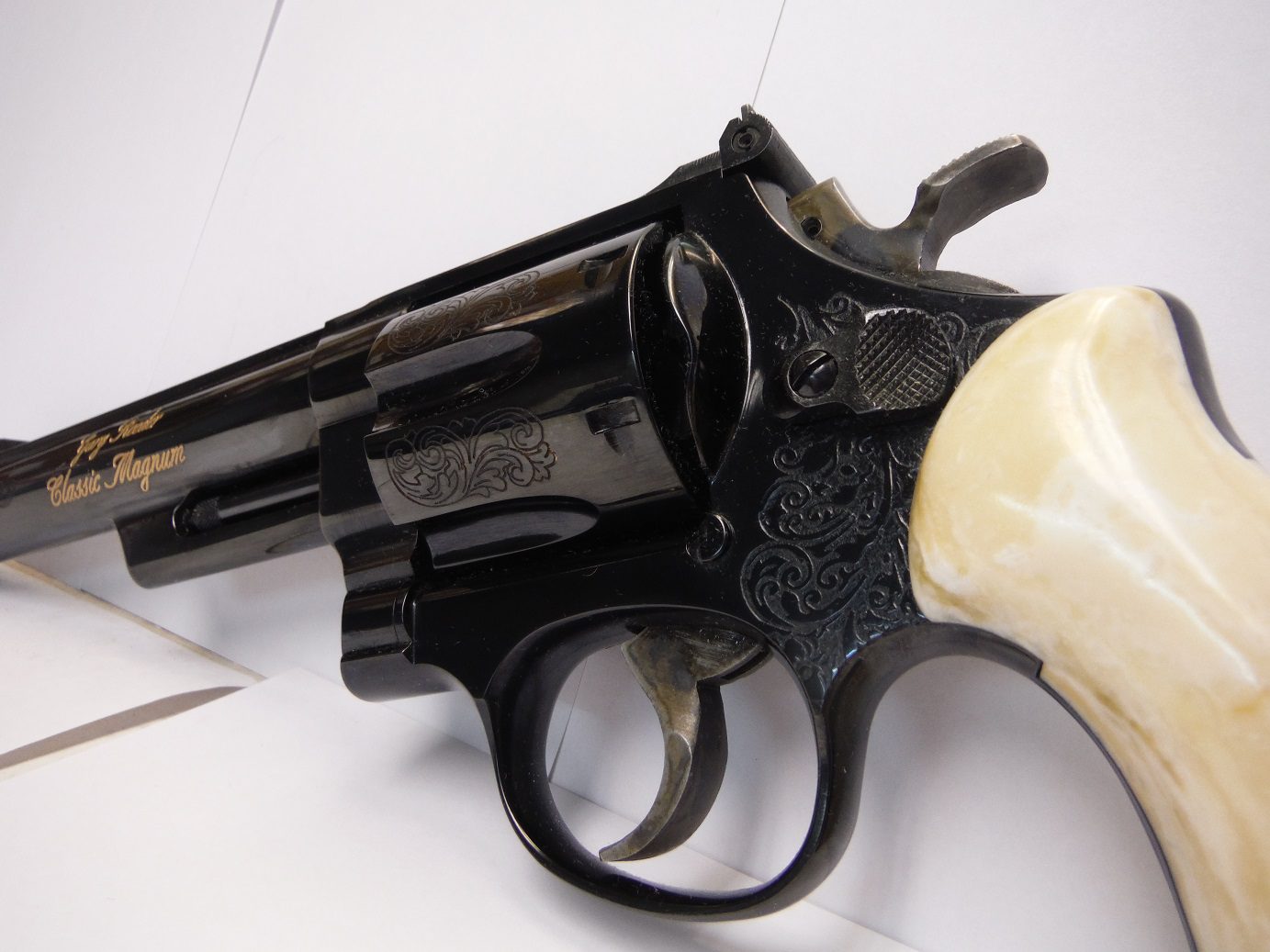 A black revolver with white handle and a bone handle.