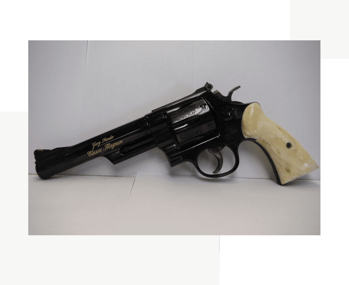 Group 25 A black revolver with white grips on top of a table.
