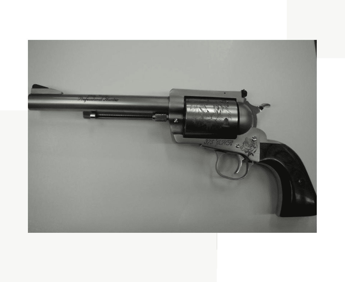 Group 51 A gun that is on the ground in front of a wall.