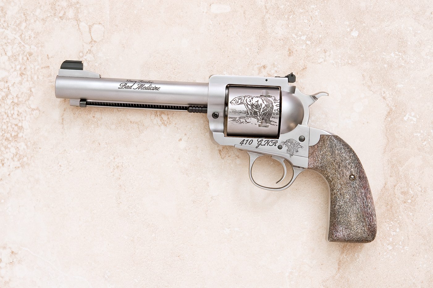 A silver gun with an engraved colt revolver on it.