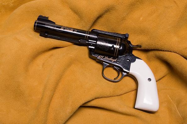 A black and white revolver is on top of a blanket.