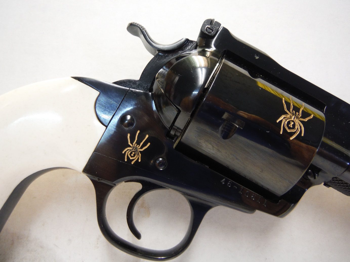 A black and white gun with gold spider on it