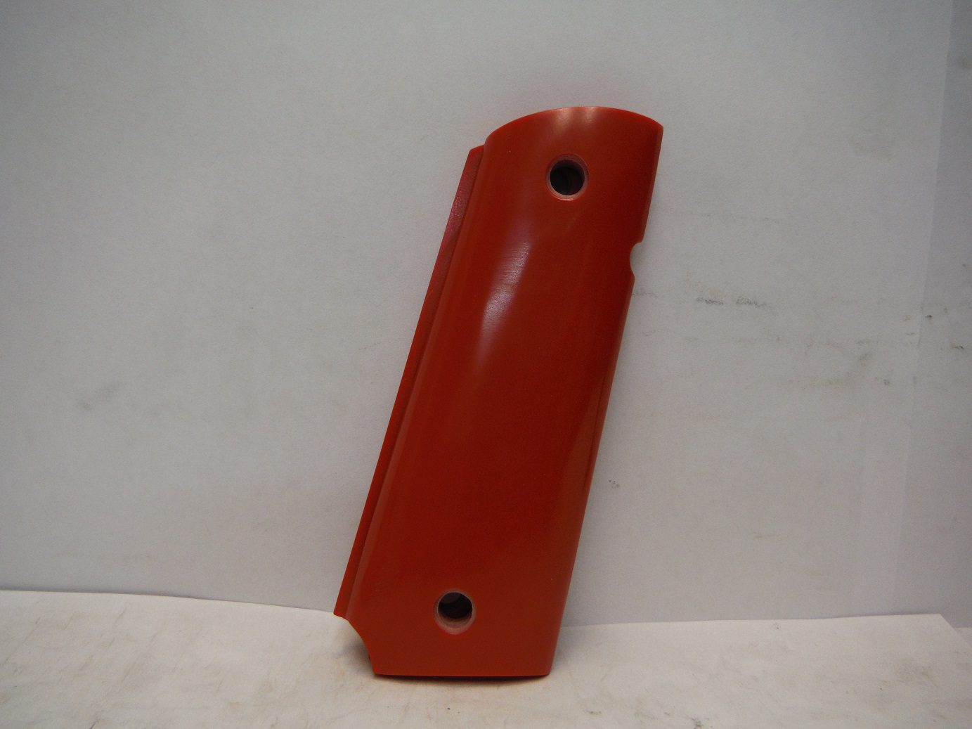 A red plastic gun handle with two holes.