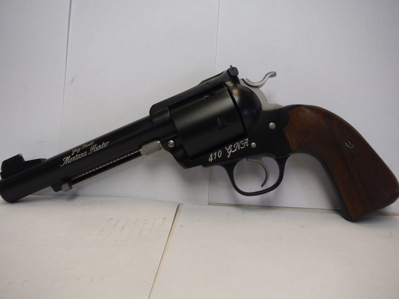 A black revolver with a wooden handle on top of it.