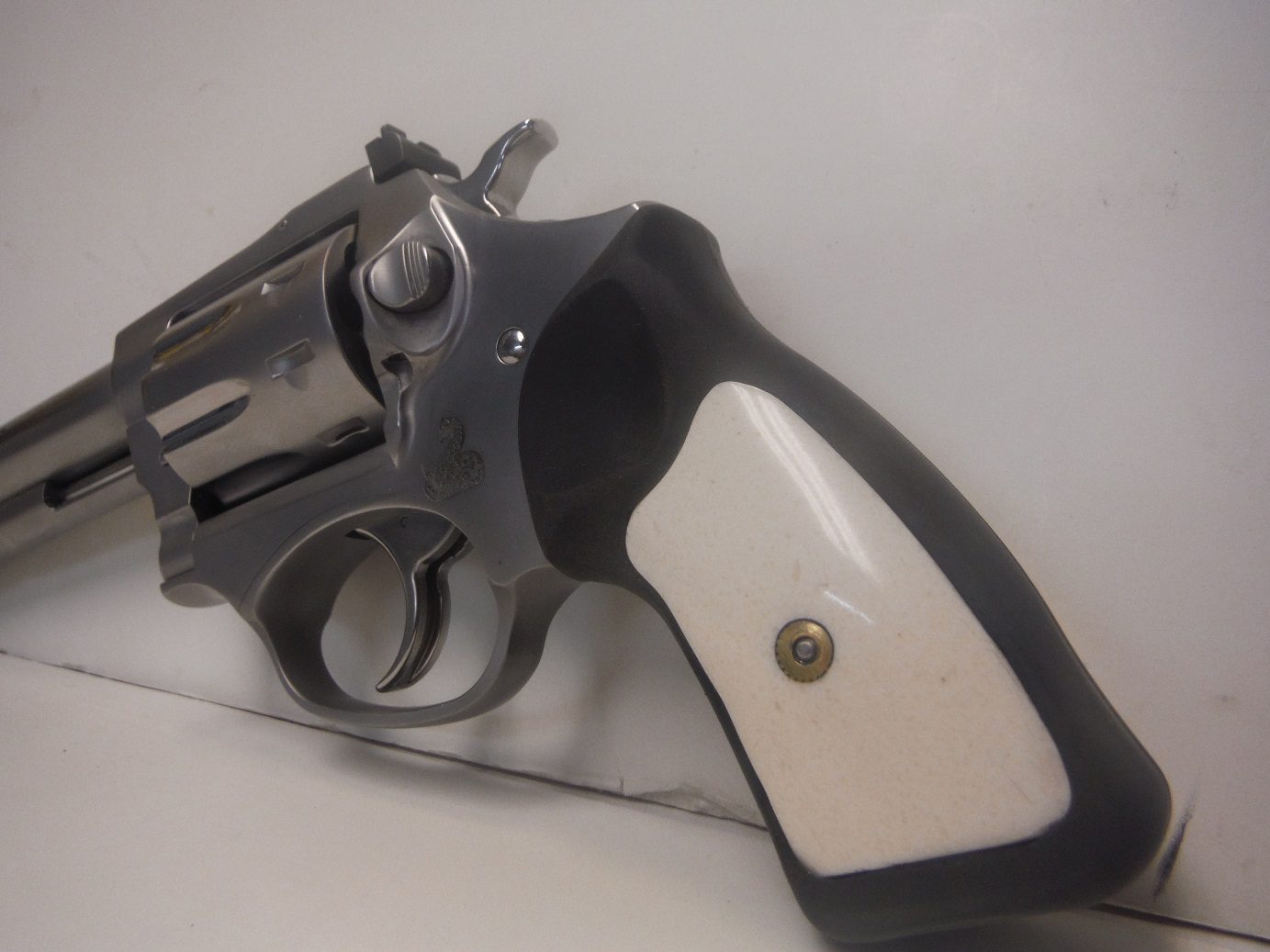 A gun that is on the ground in front of a wall.