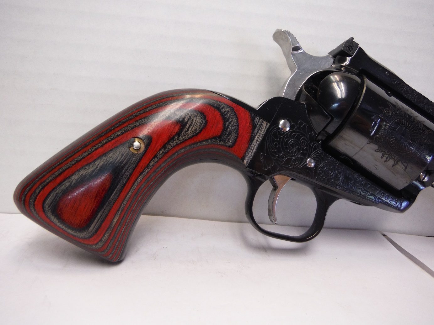 A red and black revolver is sitting on the table.